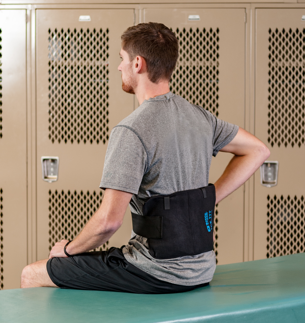Photo of a man sitting in a locker room with a large wrap on his lower back 