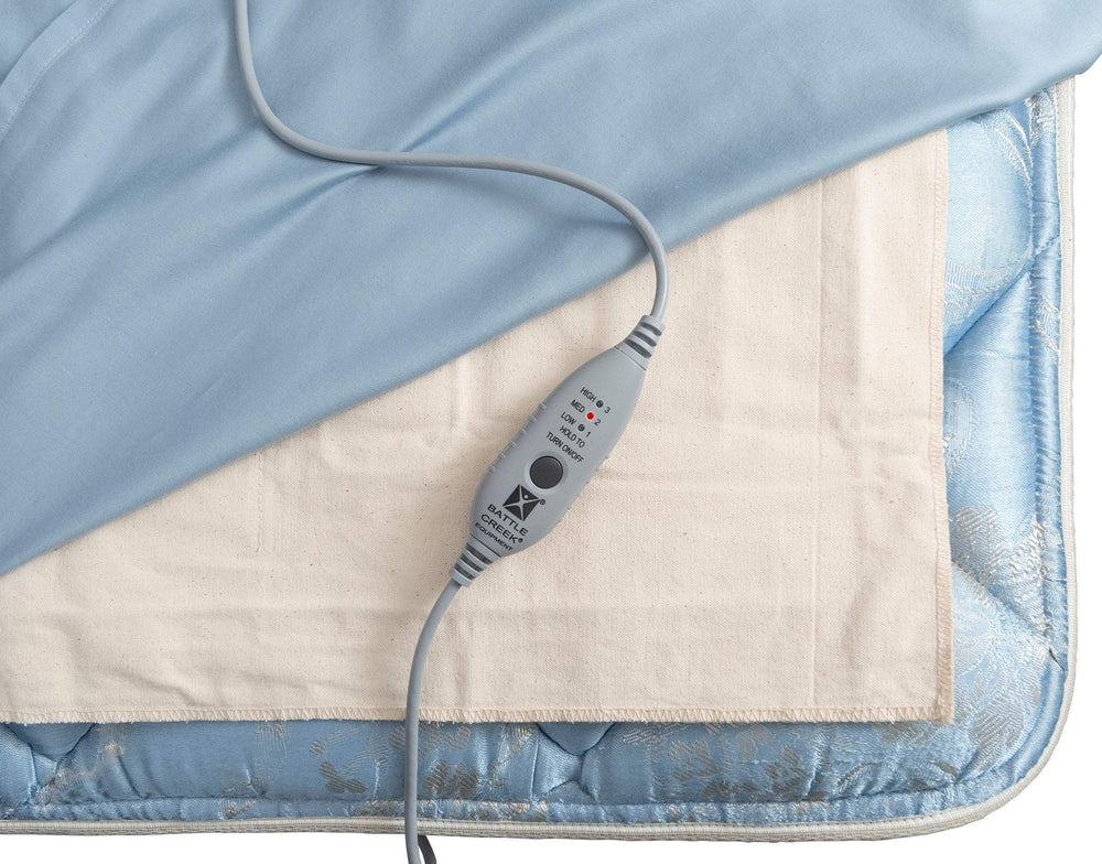 tan pad shown on a mattress with gray power cord that has 3 heat settings , a push button and battle creek written on it 